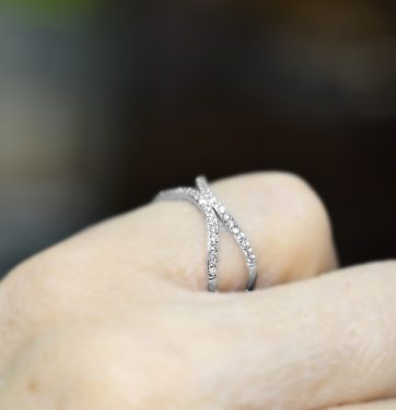 Ασημένιο δαχτυλίδι με χιαστή γάμπα διακοσμημένη με λευκές πέτρες.